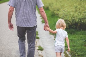 older man holding little girl's hand